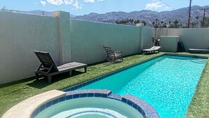 A swimming pool with a hot tub, surrounded by artificial grass and lounge chairs. - Chateau Saguaro is your home away from home (La Quinta)