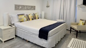 Une chambre moderne avec un grand lit, des tables de chevet blanches, une chaise et un élément décoratif mural.
