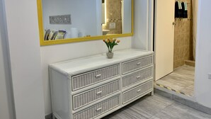 Une salle de bain avec un meuble-lavabo blanc, un grand miroir avec un cadre jaune et un espace douche.