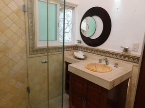 Bathroom features a glass shower enclosure, sink with a round basin, and a mirror with a circular frame.