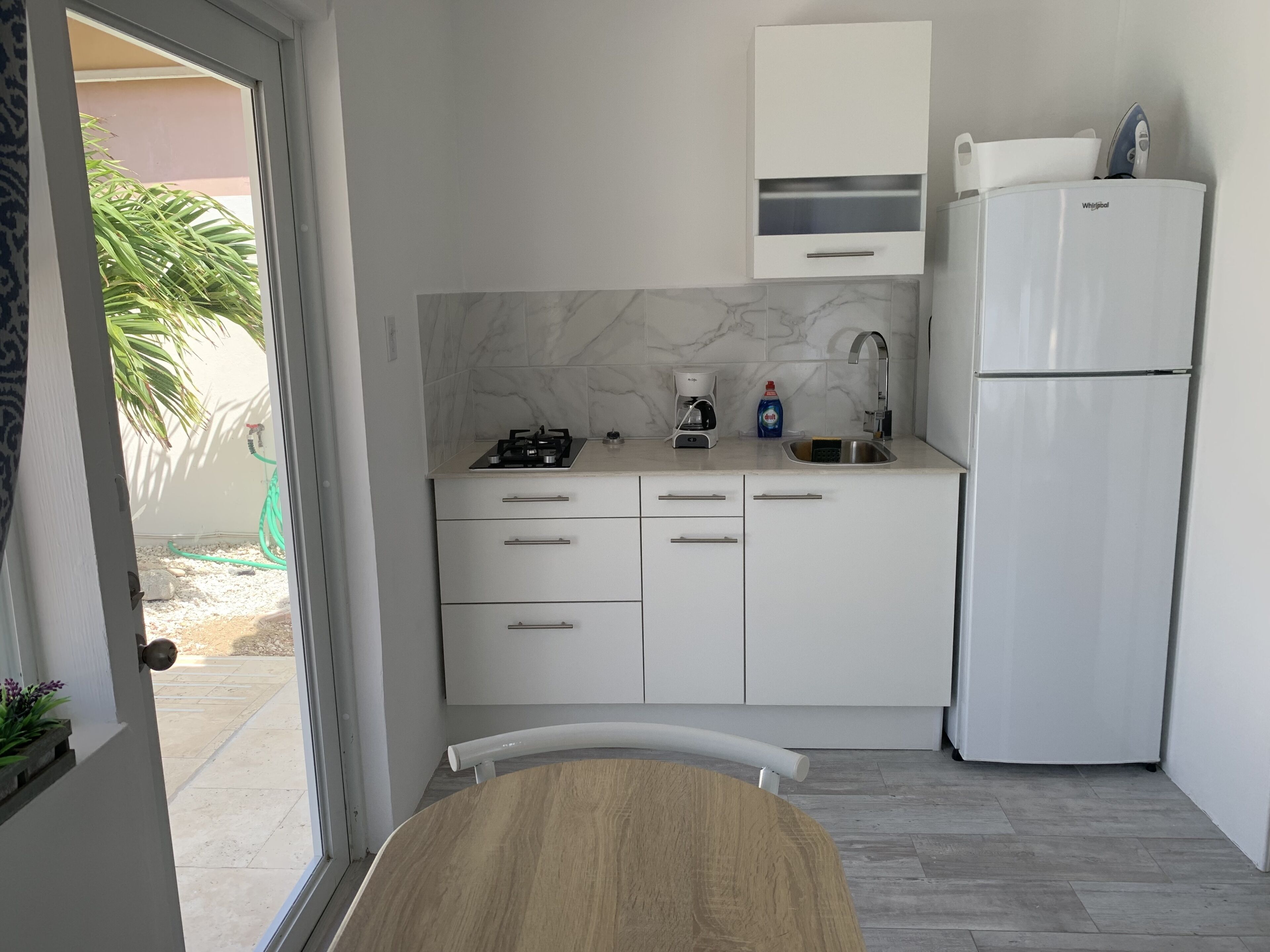 A compact kitchen with white cabinets, a built-in stove, a coffee maker, and a refrigerator.