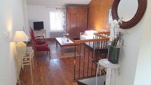 Amplia sala de estar con piso de madera, una mesa de comedor, un sofá y un televisor.