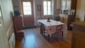 Un comedor con una mesa dispuesta para cuatro personas, suelo de madera y vista a la cocina.