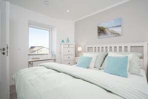 Une chambre à coucher avec un lit, une table de chevet, une commode, une fenêtre et un tableau au mur.