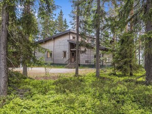 A rustic cabin surrounded by dense forest.