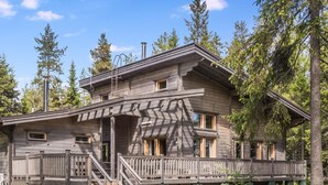 A wooden cabin with a porch, multiple windows, and a chimney.