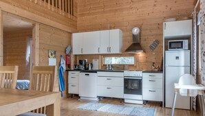 A compact kitchen with white cabinets, a stove, and a refrigerator.