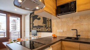 A modern kitchen with a built-in stove, a microwave, and a sink. There is a window with a view of buildings outside. - Le Curling B (Val Claret) by Interhome (Tignes)