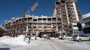 A multi-story hotel with balconies, a ground-level restaurant, and a snowy street. - Le Curling B (Val Claret) by Interhome (Tignes)