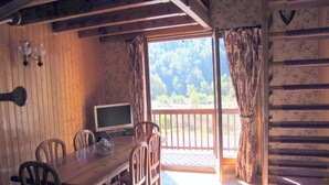 A wooden dining area with a TV, chairs, and a table. - Charming T3 "Les Cerdans" 4 seasons 2 people (Porté Puymorens)