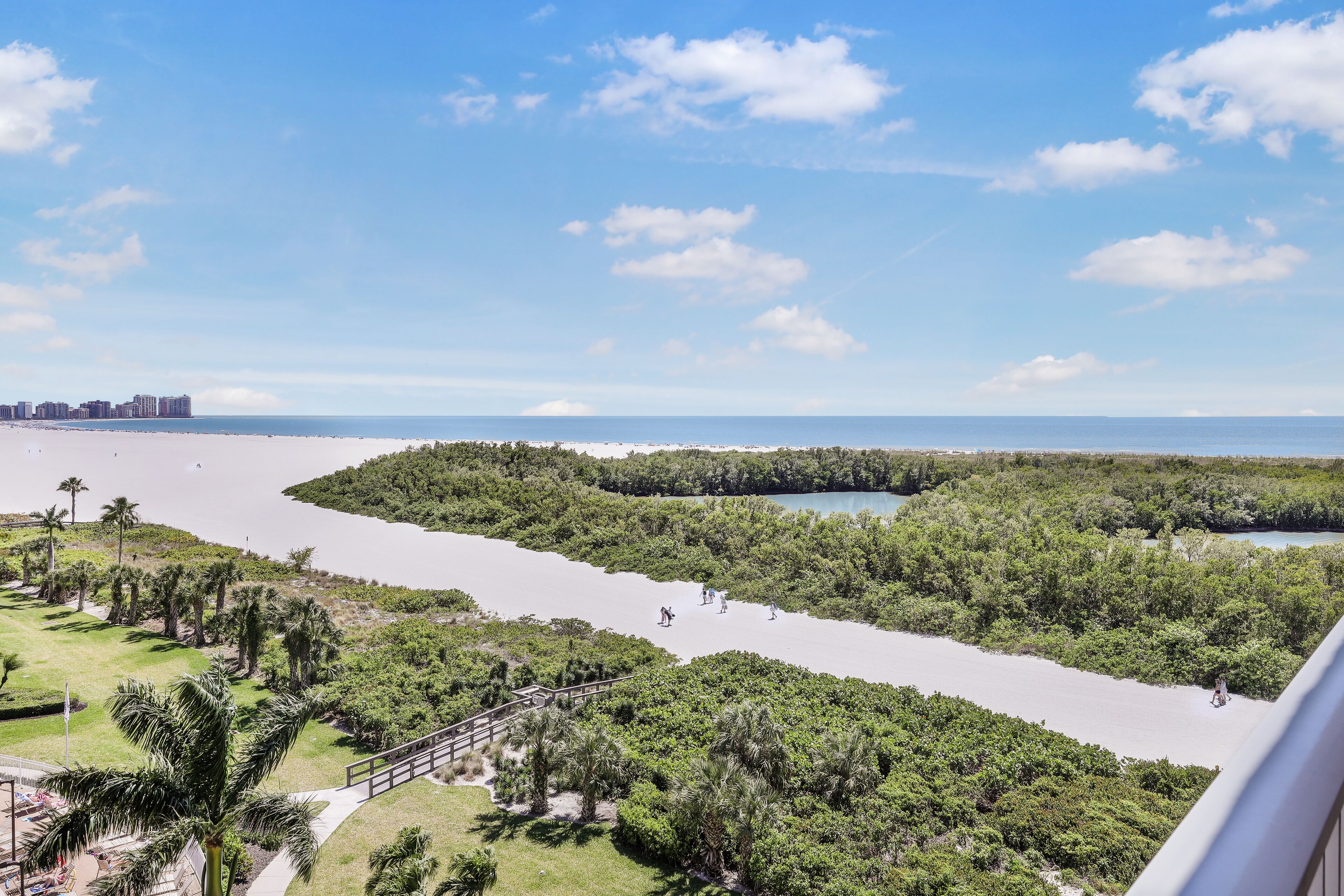 Une vue côtière comprenant une plage, une zone de mangroves et, au loin, le profil urbain d’une ville.
