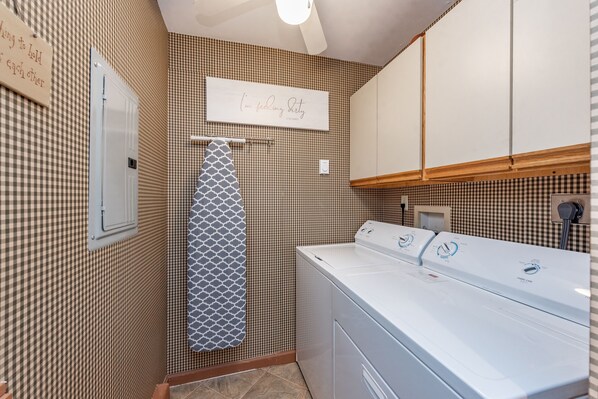 A laundry room with a large washer and dryer, a towel rack, and a sign on the wall. - Sunlit Lakefront w/ Dock, Game Room & Firepit (Oakland)
