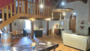 A spacious living area with a wooden staircase, a dining table, and a sofa.