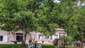 A stone building with a garden, outdoor seating, and a hammock.