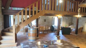 A spacious room with a wooden staircase, a table with a coffee machine, and a cozy seating area.