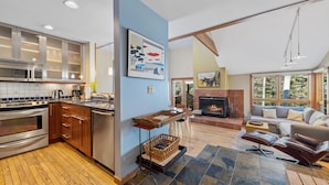 A modern kitchen with stainless steel appliances, wooden cabinets, and a blue accent wall.