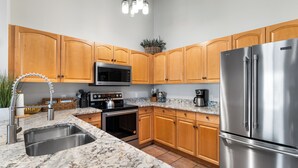 A modern kitchen with wooden cabinets, stainless steel appliances, a granite countertop, and a built-in oven. - Penthouse Condo w/ Spacious Balcony for Beautiful Views, 5 mins to Base Area! (Keystone)