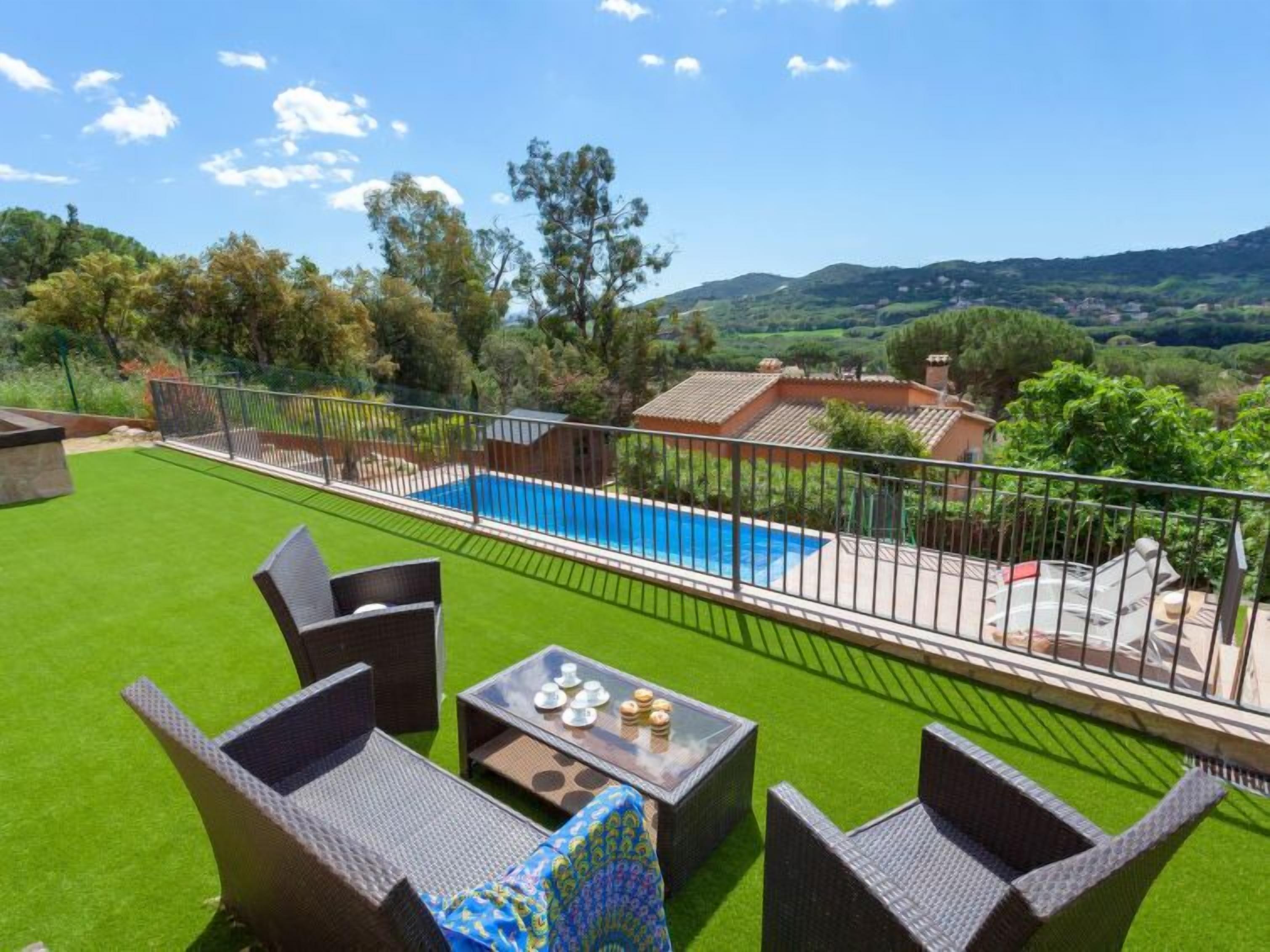 Un giardino con piscina, prato verde e mobili da esterno.