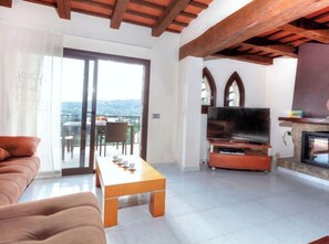 Relax in this spacious living room with a fireplace, flat-screen TV, and sliding glass door leading to a balcony with a table and chairs.