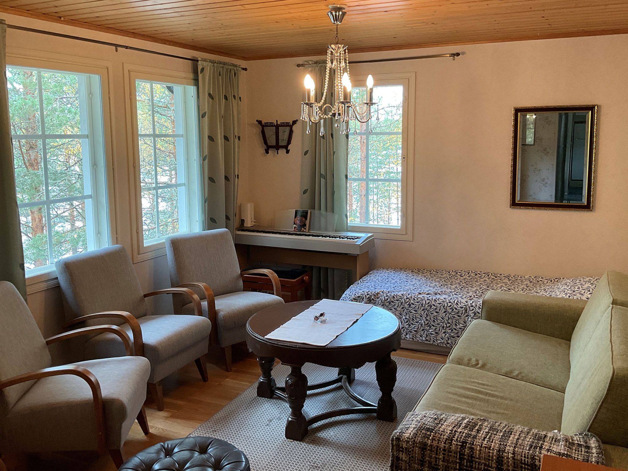 A cozy living room with a piano, seating, and a chandelier.