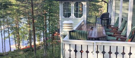 Eine Holzterrasse mit einem Gazebo, Sitzgelegenheiten im Freien und Blick auf einen bewaldeten Bereich.