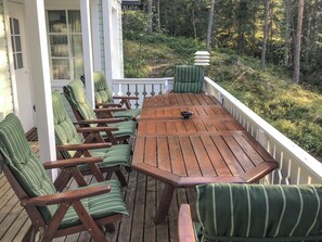A wooden deck with a table and chairs, surrounded by a white railing, overlooking a forested area. - Hiawatha by Interhome (Padasjoki)