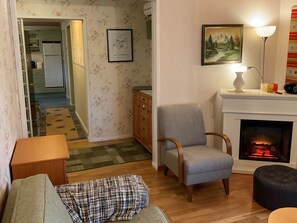 A living room with a fireplace, a sofa, a chair, a lamp, and a painting on the wall. - Hiawatha by Interhome (Padasjoki)