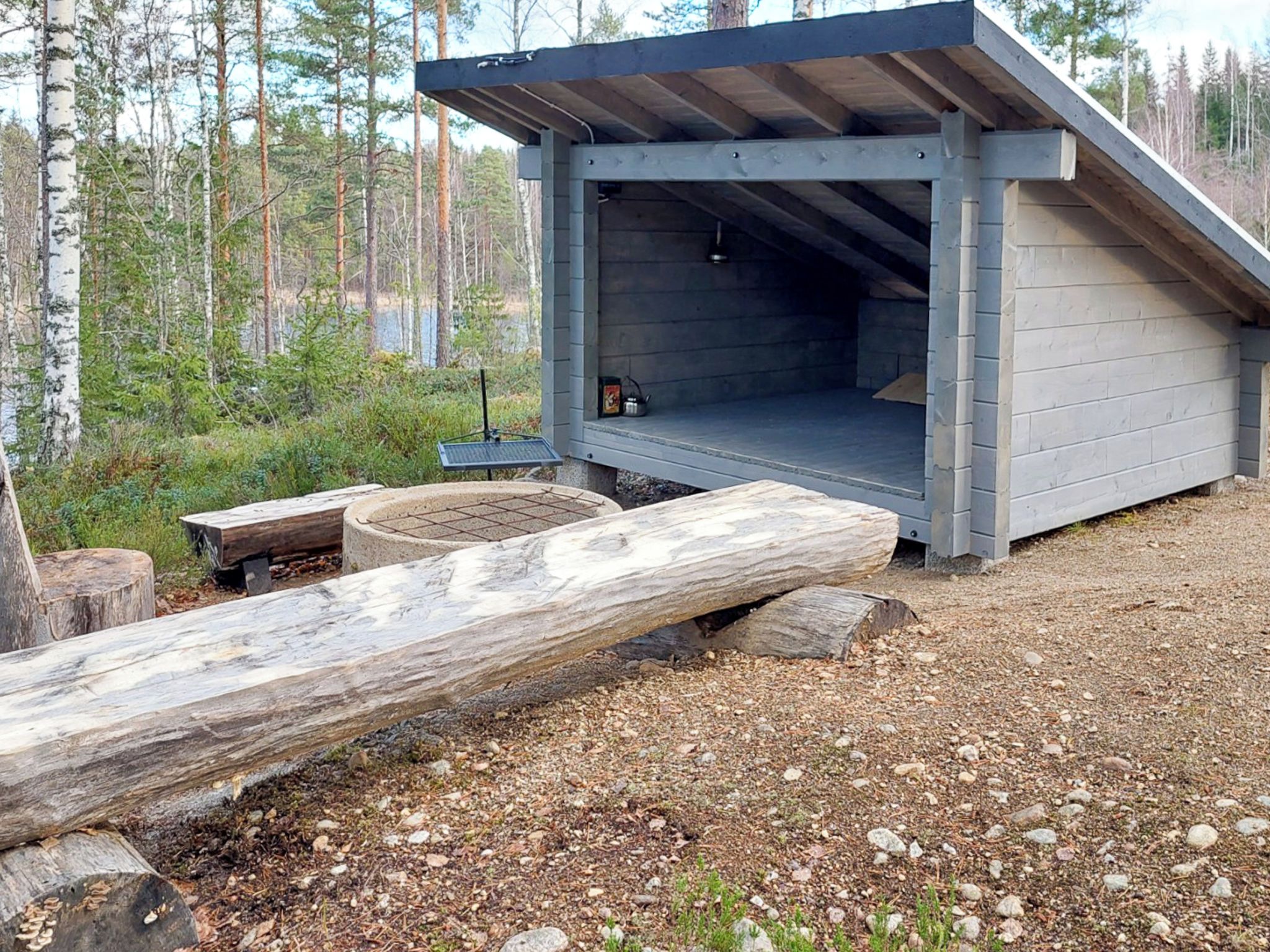 Une cabane avec un toit en pente, un foyer et une cheminée en pierre.