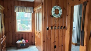 A wooden-paneled room with a window, a towel chest, and a life ring on the wall. - Waterfront Lake House Cottage Private Dock, Deck, Kayak, Boat, Swim, Fish, RELAX (Deerfield)