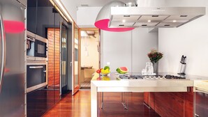 A modern kitchen with a central island, stainless steel appliances, and a bright pendant light.