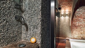 A stone shower enclosure with a built-in bench and a visible water temperature control dial.