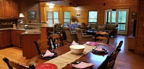 Cozy cabin interior with a rustic charm, featuring a kitchen with sink and wooden table for dining.