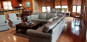 Relax in this inviting cabin-style living room with a large L-shaped sofa, dining area, and wooden floors.