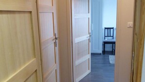 Un pasillo con puertas de madera y una silla al fondo.