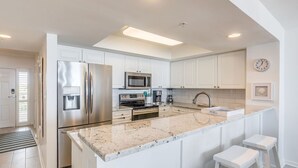 A modern kitchen with white cabinets, stainless steel appliances, a granite countertop, and a built-in oven.