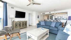A modern living room with a sofa, chairs, a coffee table, and a TV.
