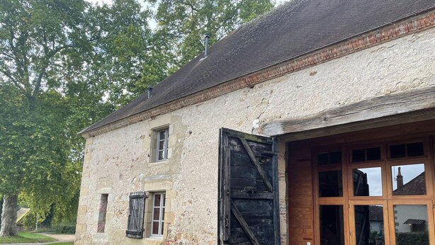 A rustic stone building with a large wooden door and windows, surrounded by greenery. - Restored Shepherd's Hut, Pets Allowed (Sauvagny)