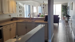 A modern kitchen with a central island, built-in cabinets, and a large window providing natural light. - Oceanfront Corner 2BR Condo 2nd Floor Balcony Indian Harbour Beach, Unit 208 (Indian Harbour Beach)