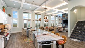 A spacious kitchen with a large island, modern appliances, and a dining area with comfortable seating. - Huge Ocean View - Spa/Pool/Golf Cart (Port Aransas)