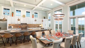 A spacious kitchen with white cabinets, a large island, and a dining area with a table set for six. - Huge Ocean View - Spa/Pool/Golf Cart (Port Aransas)