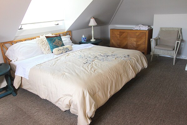 A bedroom with a large bed, a nightstand, a chair, and a dresser.