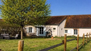 A rustic building with a brick roof, a wooden fence, and a tree in the foreground. - Country house, AC - 4 guests (Saint-Bonnet-Tronçais)