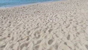 A sandy beach with clear blue water and a clear sky.