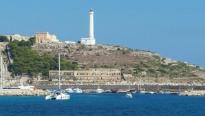 A coastal town with a prominent lighthouse, a historic building, and a marina with boats.