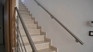 A staircase with a metal handrail and beige steps.
