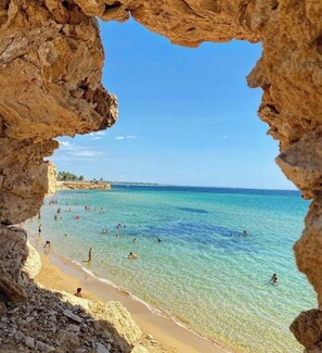 A beach with clear turquoise water, visible rocks, and a sandy shore. - Villa Iblea Private Pool & Sunset Hill Views (Avola)