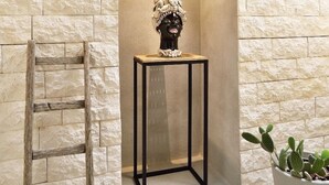 A stone wall with a small table and a potted plant. - La Perpetua - The Space of Mima (Noto)