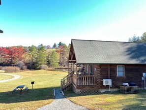 Eine Blockhütte mit Veranda, einer kleinen Terrasse und einem Kiesweg, der dorthin führt.