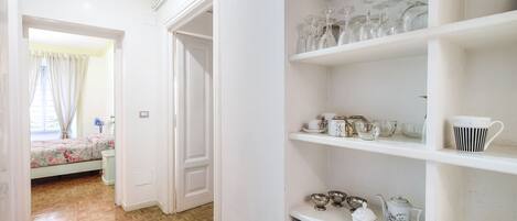 Une pièce avec un plancher en bois, un lit recouvert d’une literie à motifs floraux et une porte blanche.