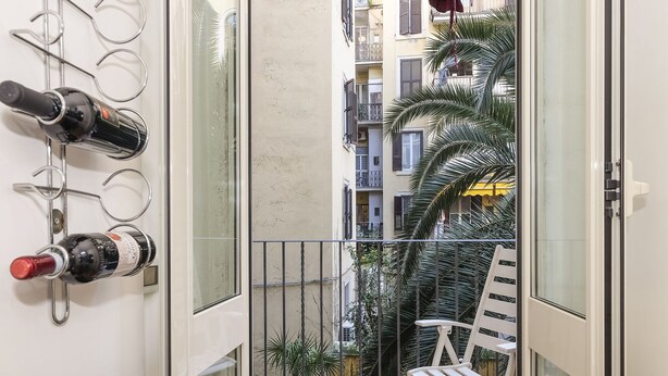 Un balcone con una sedia bianca e un portabottiglie pieno.